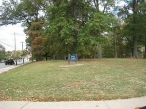 large park with trees and sign in front