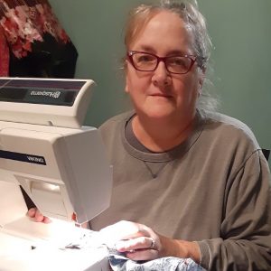 Parks volunteer Janell sitting by sewing machine making masks